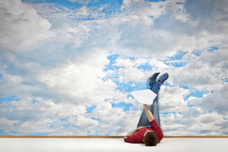 Young man lying on floor with legs raised upの写真素材