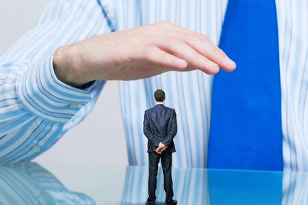 Miniature of businessman in palm protected with careの写真素材