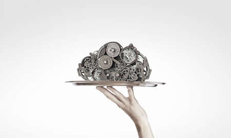 Hand serving metal gears on silver trayの写真素材