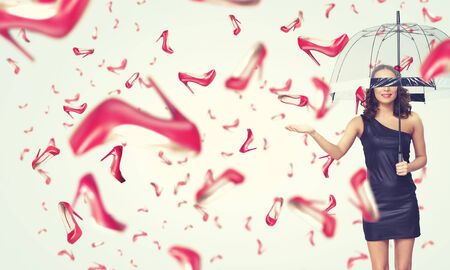Beautiful young woman with umbrella and falling shoesの写真素材
