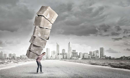 Young girl in casual carrying stack of carton boxesの写真素材