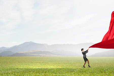Young businesswoman in suit and bowler hat pulling curtainの写真素材