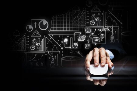 Hand of businessman in suit on dark background using wireless computer mouse