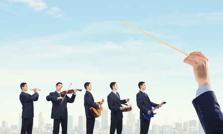 Man orchestra in suit playing different music instrumentsの写真素材