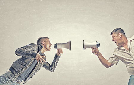 Young man and elder one screaming aggressively in megaphone on each other