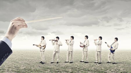 Man orchestra in suit playing different music instrumentsの写真素材