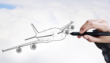 Person drawing airplane model on sky background