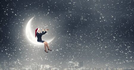 Woman in formal suit and Santa hat looking in spyglassの写真素材