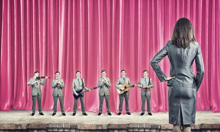 Man orchestra playing different music instruments and woman leader