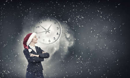 Woman in suit and Santa hat with arms crossed on chest