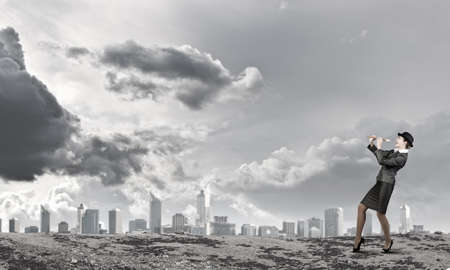 Cheerful businesswoman in suit and bowler hat playing fifeの写真素材