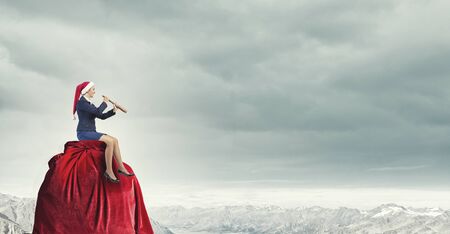 Woman in formal suit and Santa hat looking in spyglassの写真素材