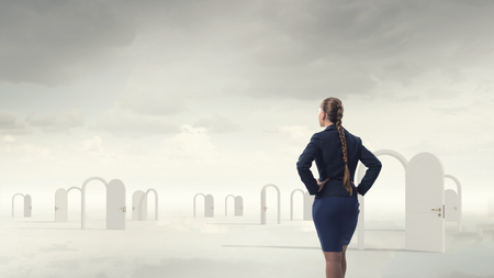 Businesswoman standing in front of opened doors and making decisionの写真素材