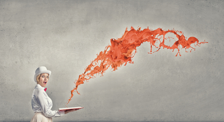 Young woman in white hat with opened book in hands and splashes flying outの写真素材