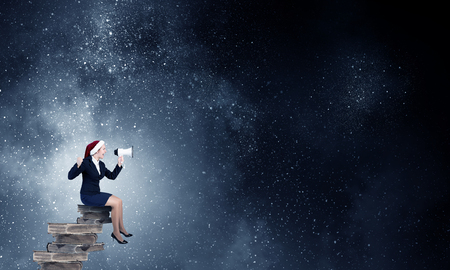 Woman in suit and Santa hat shouting into megaphoneの写真素材