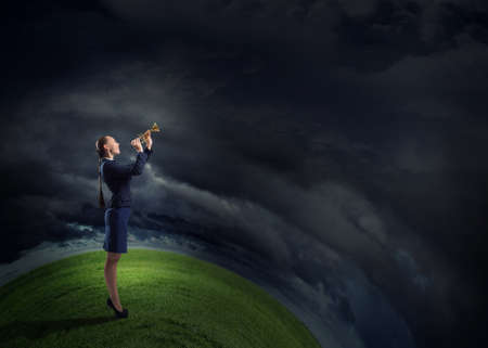 Young pretty businesswoman playing melody on trumpetの写真素材