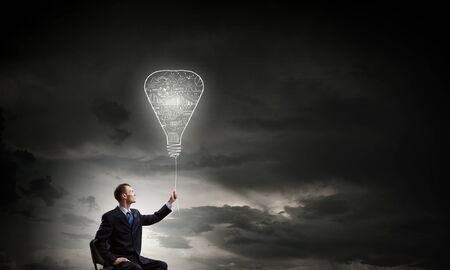 Businessman with bulb on rope representing bright ideaの写真素材