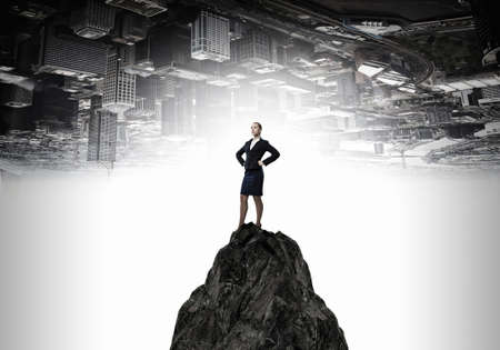 Confident businesswoman with arms on waist standing on topの写真素材