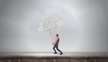 Young man carrying in hands heavy big successful idea conceptの写真素材