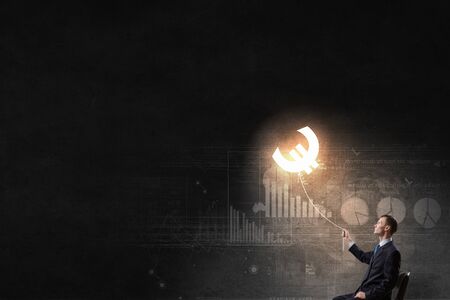 Businessman catching glowing euro currency symbol with ropeの写真素材