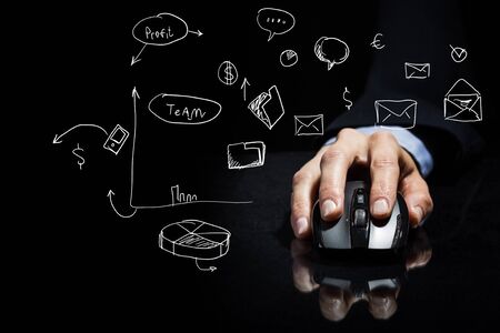 Hand of businessman in suit on dark background using wireless computer mouse