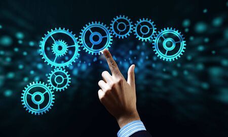 Close up human hand pointing with finger at gears mechanismの写真素材