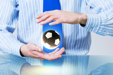 Hands of businessman holding with care soccer ballの写真素材