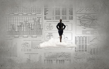 Rear view of businesswoman looking at infographs on wallの写真素材