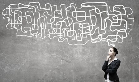 Young pensive businesswoman and arrows coming out of her headの写真素材