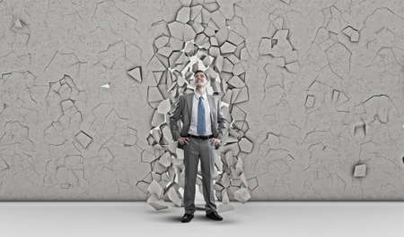 Young powerful businessman breaking through cement wallの写真素材