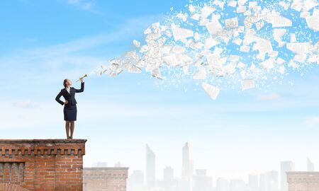 Young pretty businesswoman playing melody on trumpetの写真素材