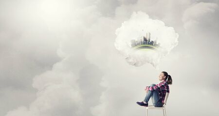 Teenager girl sitting in chair and cloud bubble above her headの写真素材