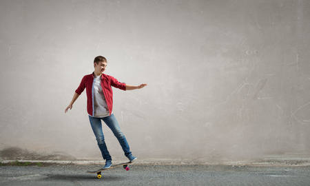 Handsome teenager cool acive boy riding skateboardの写真素材