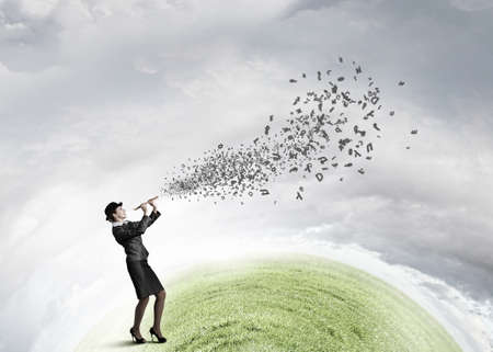 Cheerful businesswoman in suit and bowler hat playing fifeの写真素材