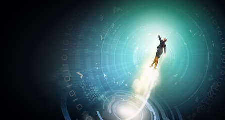 Businesswoman hero in suit flying up into skyの写真素材