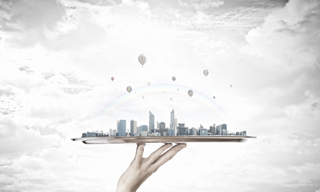 Hand holding metal tray with modern city modelの写真素材