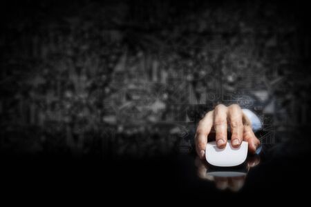 Hand of businessman in suit on dark background using wireless computer mouseの写真素材
