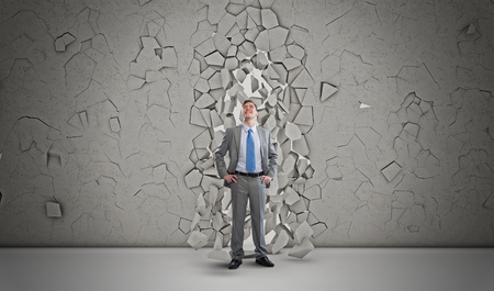 Young powerful businessman breaking through cement wallの写真素材
