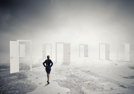 Businesswoman standing in front of opened doors and making decisionの写真素材