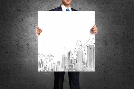 Businessman holding banner with urban construction conceptの写真素材