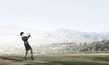 Cheerful businesswoman in suit and bowler hat playing fifeの写真素材