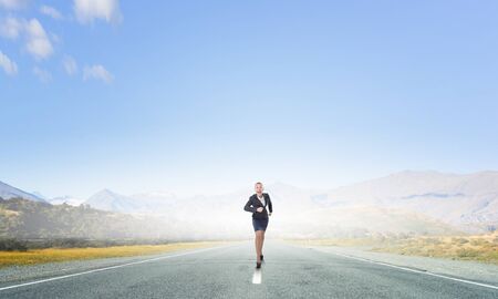 Young determined businesswoman competitor running on roadの写真素材
