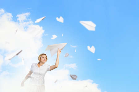 Young carefree woman with paper plane in handsの写真素材