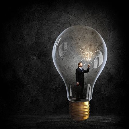 Businessman inside of glass light bulb on dark backgroundの写真素材