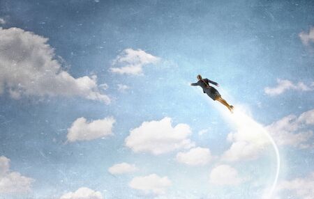 Businesswoman hero in suit flying up into skyの写真素材