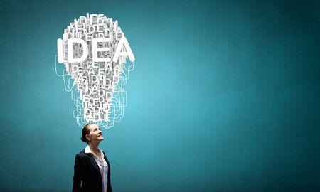 Young pensive businesswoman and ideas coming out of her headの写真素材