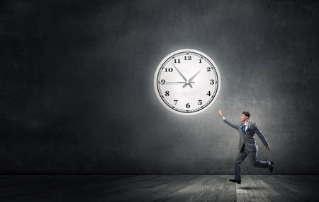 Businessman running and trying to catch timeの写真素材