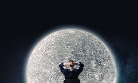 Rear view of businessman sitting on chair with hands on headの写真素材