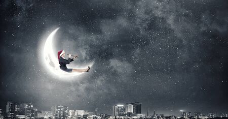 Woman in formal suit and Santa hat looking in spyglassの写真素材