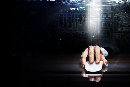 Hand of businessman in suit on dark digital background using wireless computer mouseの写真素材
